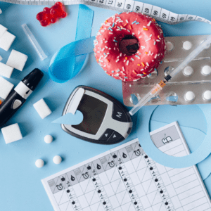 An assortment of tools needed to manage diabeties- blood sugar meter, insulin in a syringe, finger stick, as well as sugary treats like doughnuts and gummy bears.